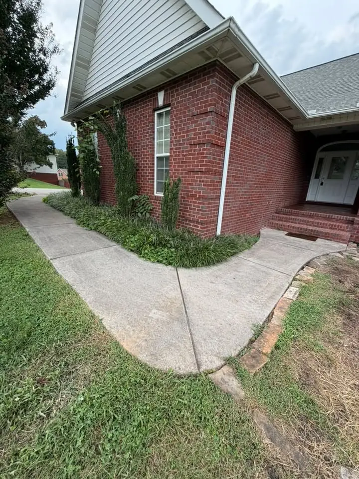 Plain gray concrete walkway alongside a brick home before replacement in Maryville, Tennessee